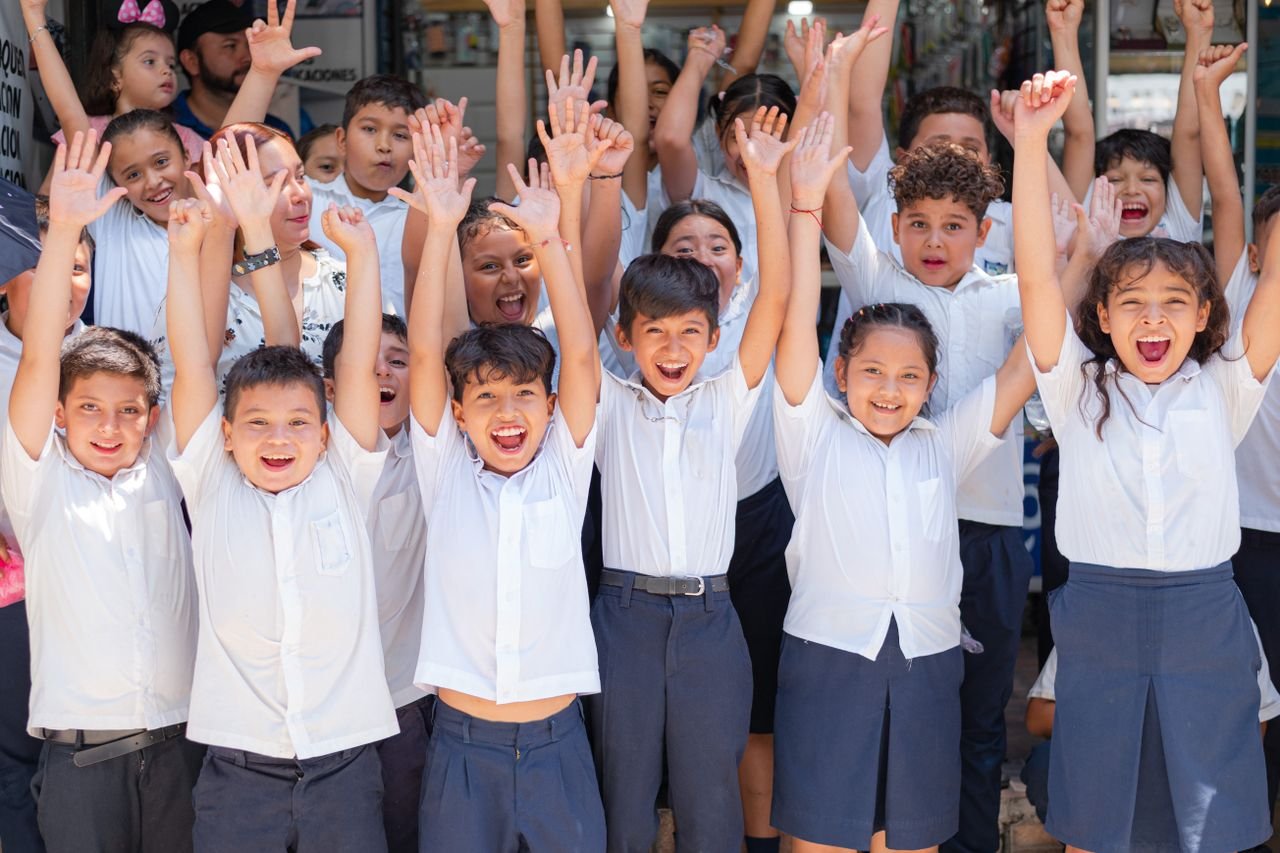 Joyful group of school children in Santa Rosa de Lima, El Salvador cheering outdoors.