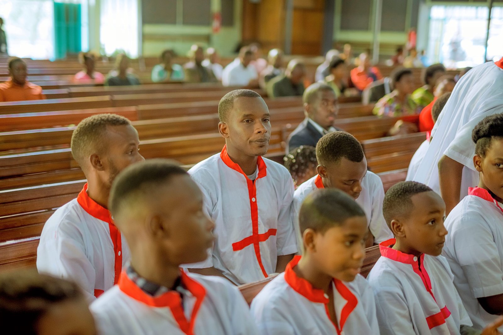 A group of people in matching white and red robes attending a religious service in a church.