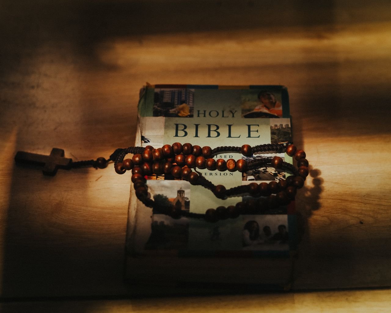 A Bible with rosary beads in warm, dramatic lighting, symbolizing faith.