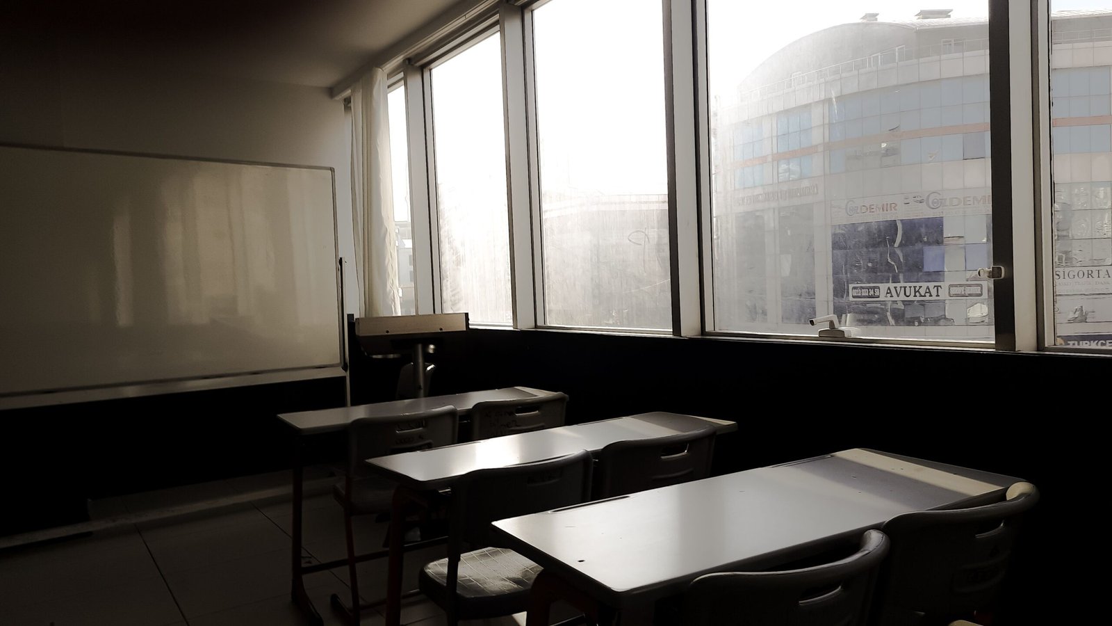 Sunlit empty classroom in Istanbul, featuring desks and a whiteboard.